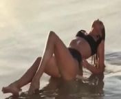 Candice Swanepoel laying on beach in black bikini from black bikini outdoor